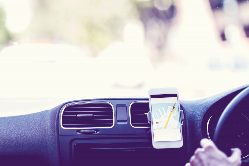 Taxi driver using GPS to follow the route. Travelling with GPS. Taxi (fictive) application on smart phone in action.